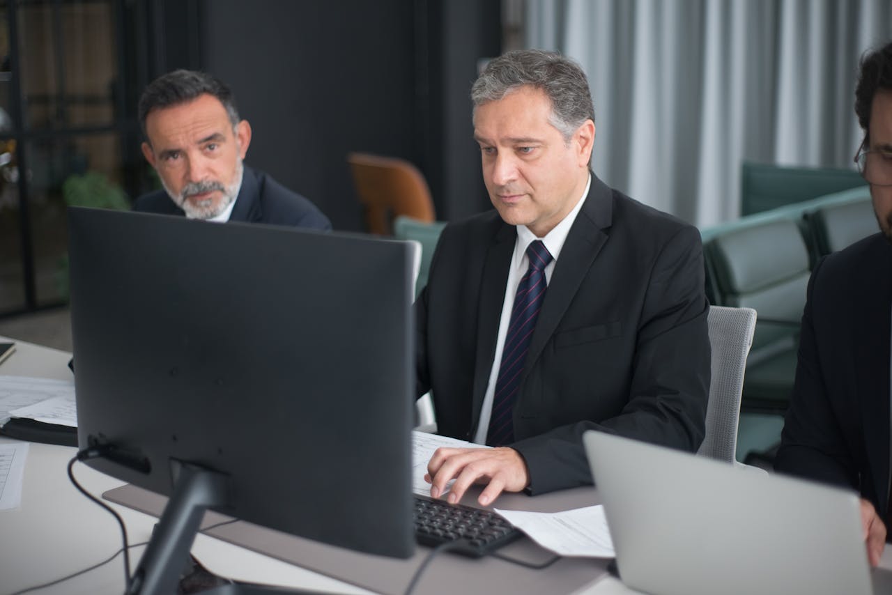 Professionals in a modern office engaged in a business meeting with computers.